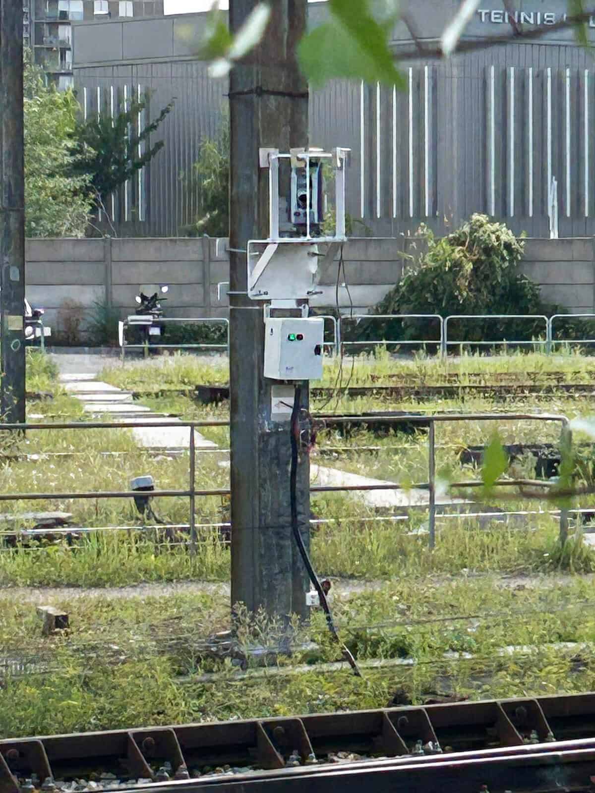 Poteau électrique avec équipements de surveillance et câblage en extérieur.