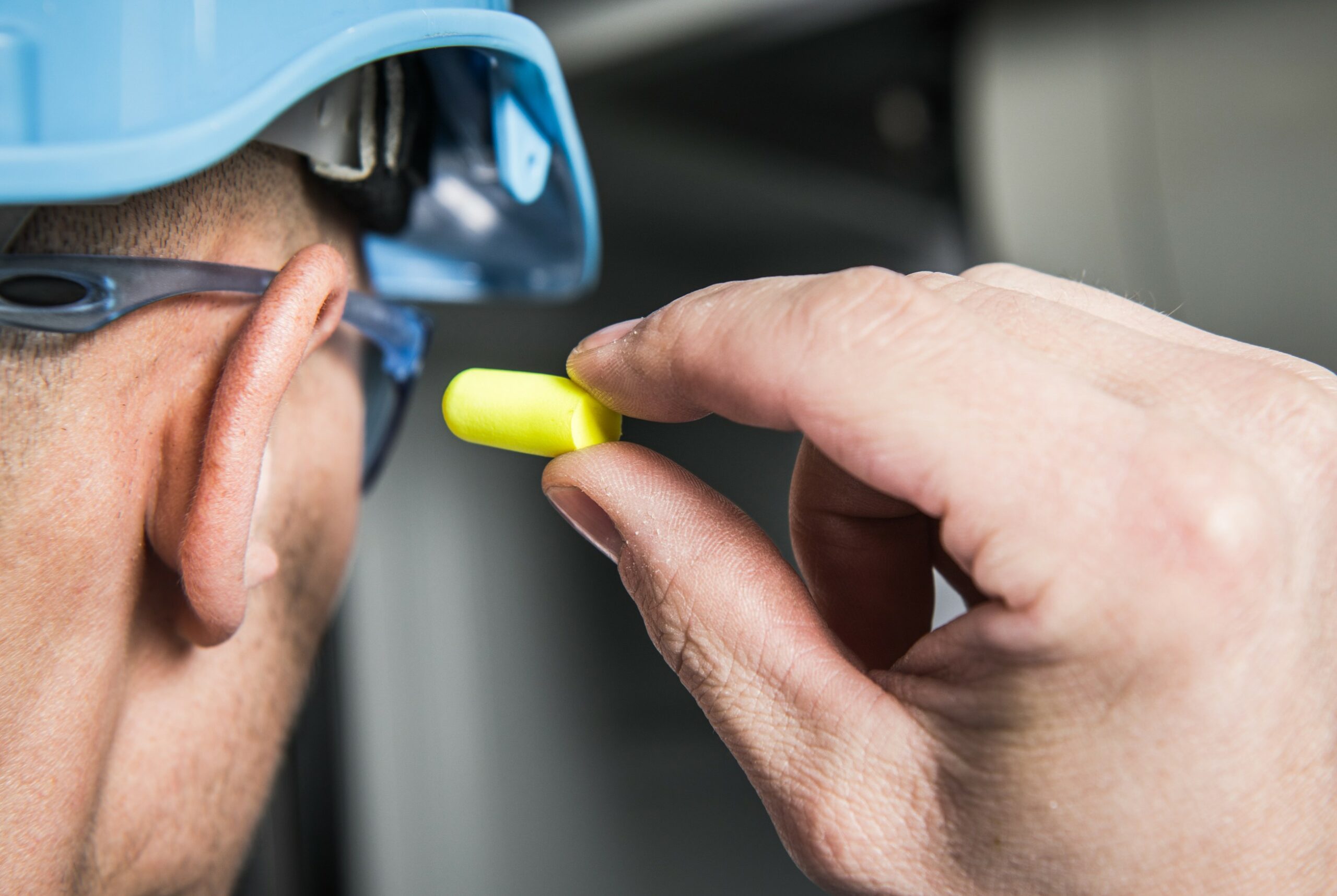 A man on a construction site putting on ear protection